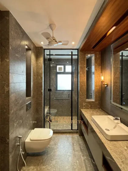 A practical and stylish bathroom with dark marble-patterned tiles, a glass shower partition, and a floating vanity with wood accents.