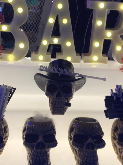 A fun and edgy shooter station with skull-shaped mugs and a light-up 'BAR' sign.