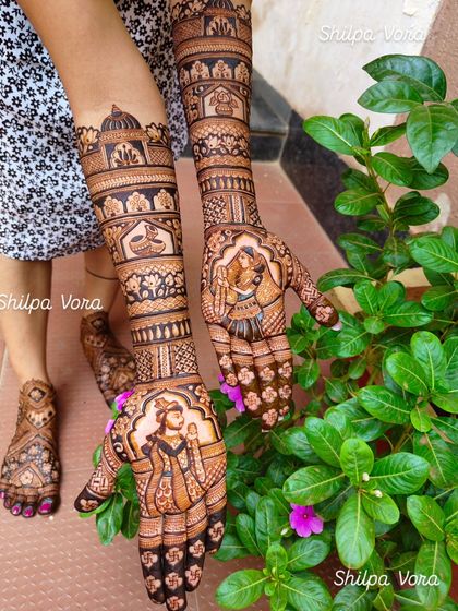 Full bridal mehndi extending up the arms, featuring portraits of a royal-looking couple. This design is perfect for a bride who wants a grand and traditional look.