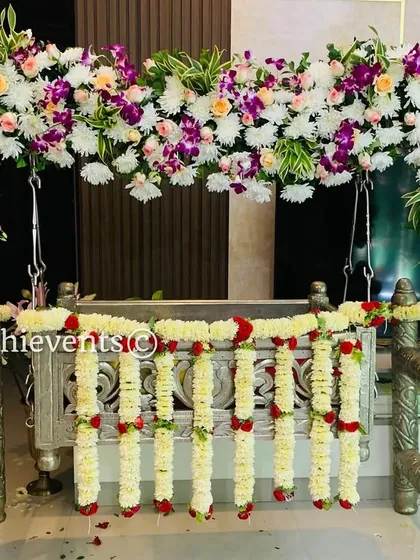 A beautiful silver cradle decorated with an arch of orchids and other exotic flowers. This modern and stylish floral arrangement is perfect for a contemporary naming ceremony.