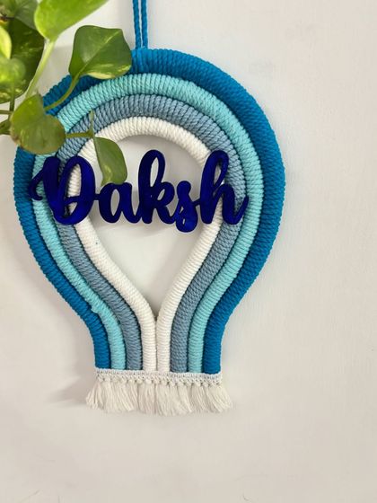 Another angle of the blue parachute name hanging for Daksh, showing how it looks against a wall with a bit of greenery.