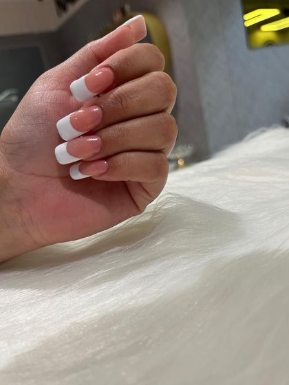 A close-up of a flawless French manicure on square-tipped extensions. The lines are sharp, the finish is glossy, and the look is pure elegance.