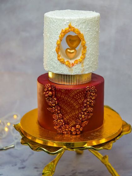 We are always learning and practicing new modern art techniques. This two-tier cake features a unique window design with a golden heart inside, and the bottom tier is decorated with intricate golden lace.