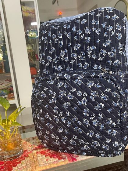A three-quarter view of the quilted organizer backpack, featuring a lovely blue floral fabric and vertical stitching.