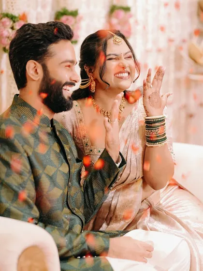 A candid shot of the couple laughing as they are showered with petals during their engagement ceremony.