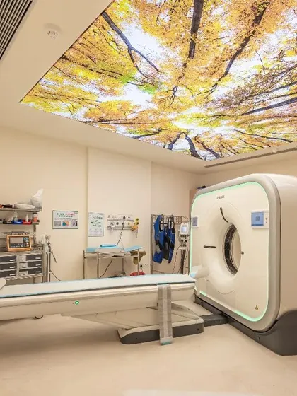 To mitigate patient anxiety in diagnostic settings, we incorporate principles of biophilic design. This PET CT scan room features a luminous ceiling panel depicting a natural forest canopy, creating a calming visual focus that transforms the clinical experience and supports patient well-being during procedures.
