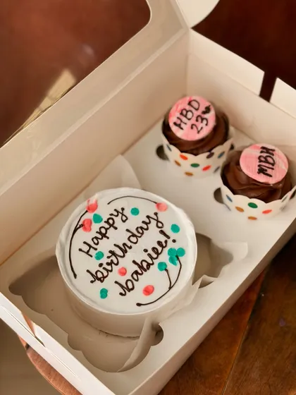 A fun and colorful Dutch truffle birthday combo. The bento cake has a confetti-like design, and the two chocolate cupcakes are personalized for a 23rd birthday.