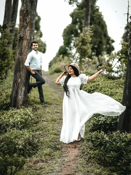 A playful and dynamic shot of the bride twirling her dress in a forest path, with the groom looking on. This image is full of life, movement, and the joy of being in nature together.