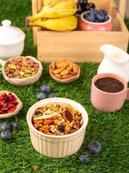A bowl of granola and nuts set against a vibrant green, grassy background. This styling emphasizes the natural and healthy qualities of the product.