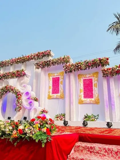 A beautiful white and pink themed stage, perfect for a daytime reception. The design uses ornate frames and a floral arch to create a romantic and whimsical backdrop.