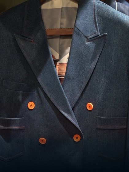 A detailed shot of a double-breasted denim blazer. The focus is on the lapels and button placement, illustrating our precision in tailoring even with casual fabrics.