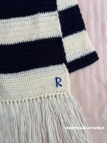 A close-up of the hand-embroidered initial 'R' and the neat fringe on our custom striped muffler.