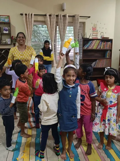 A joyful group shot with the storyteller, as children hold up the "Hairy Hettie" puppets they crafted.