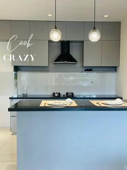 This kitchen features an island with a breakfast counter, pendant lighting, and a sleek combination of light grey and white cabinets for a clean, contemporary look.
