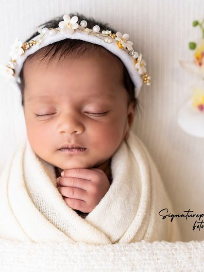 A newborn wrapped in white, sleeping peacefully amidst delicate white orchids.