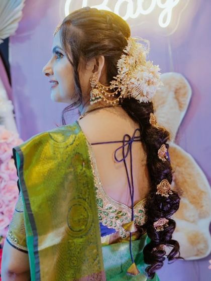 A side profile of a client at her baby shower, showing off her beautiful hair accessory and traditional South Indian earrings.