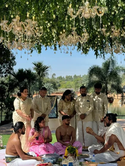 A traditional puja being performed during the Nischitartham ceremony, set under a stunning canopy of greenery and crystal chandeliers.