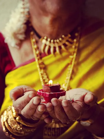 A photo celebrating Dhanteras, with hands holding a small diya. This image represents the wealth, health, and prosperity that we wish for our families during the festive season.