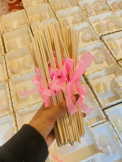 This image shows the reed diffuser sticks we include in our hampers, bundled with a pink ribbon. It's the small details that make our gift sets special and complete.