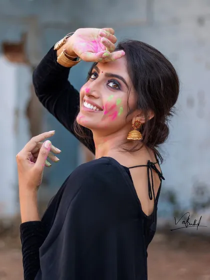The pure joy of Holi captured in a candid moment. This portrait focuses on the vibrant colors and the model's infectious smile, blending traditional festival fun with a contemporary fashion aesthetic in a black saree.