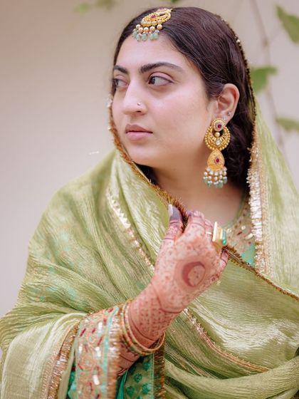 A close-up of the bride, showcasing her traditional jewelry and the beautiful henna design on her hand.