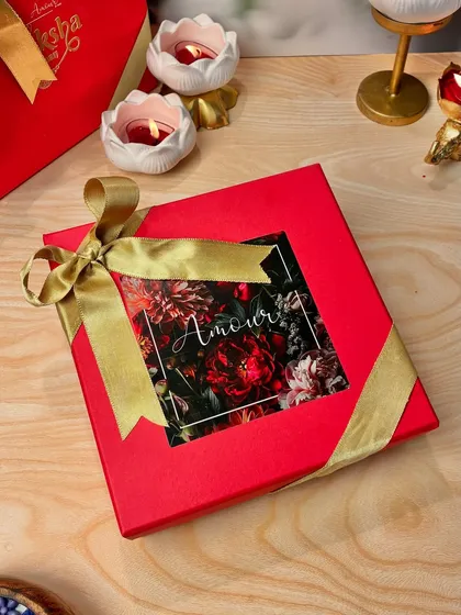 The complete Rakhi gift, beautifully packaged. This vibrant red box, tied with a gold ribbon, holds a special handcrafted candle to make your sibling feel loved.