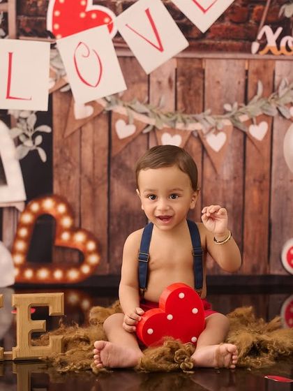 A Valentine's Day themed first birthday shoot. We used a rustic backdrop with hearts and balloons to create a warm and loving atmosphere for this little one's celebration.