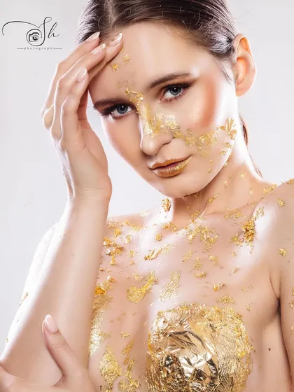 A beauty-focused editorial shot of a model with gold leaf applied to her skin. We excel in creative beauty photography, playing with textures and light to create fine art-style portraits.