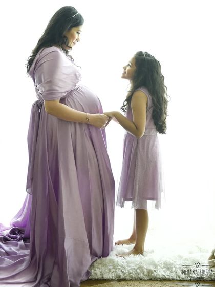 A beautiful high-key portrait of a mother and daughter sharing a moment of anticipation. The matching lavender dresses and the tender look between them create a truly magical image.