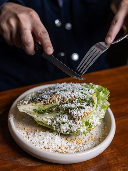 A salad so good, it’ll make you love greens. A guest enjoys 'The Manor' Caesar, cutting into the crisp wedge of iceberg lettuce covered in parmesan.