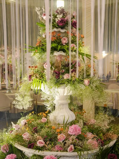 A detailed shot of the floral fountain, highlighting the rich variety of blooms and the delicate baby's breath that creates a soft, cloud-like effect at the base.