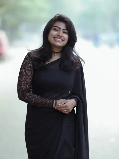 An elegant and modern look for a photoshoot. The makeup is kept minimal and fresh to complement the classic black saree, showing that simplicity can be incredibly powerful.