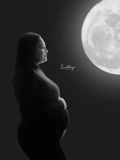 A contemplative solo silhouette of a mother-to-be looking towards the moon. This black and white shot is filled with a sense of wonder and anticipation.