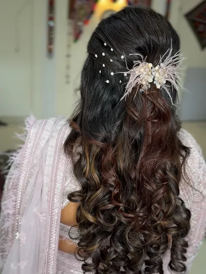 A romantic half-up style with a feathered hair accessory. The combination of soft curls and delicate details creates a dreamy and ethereal look.