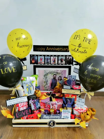 This anniversary hamper is a celebration of '4 years of love'. It's loaded with snacks, personalized with a framed photo and film strip, and includes festive balloons with custom messages.