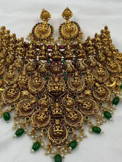 A detailed South Indian temple jewellery necklace with goddess Lakshmi motifs and green bead drops.
