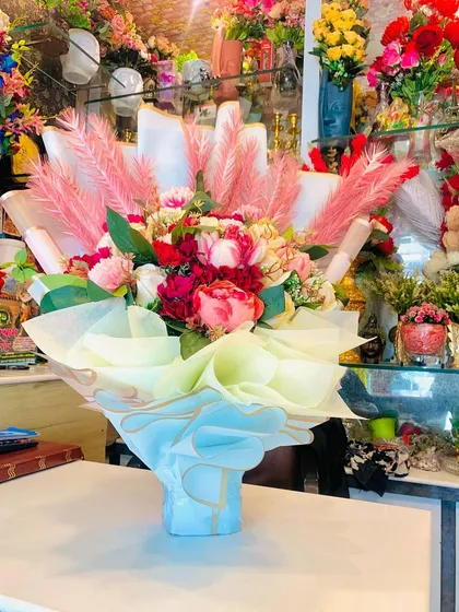 A side view of the large artificial bouquet, showing the beautiful pastel-colored wrapping that complements the flowers.