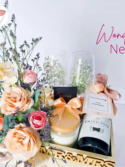 Our "Wonder Nest" hamper is perfect for a couple. It includes Mr. & Mrs. themed items, a scented candle, a bottle of non-alcoholic wine, and a beautiful floral arrangement with peach roses.