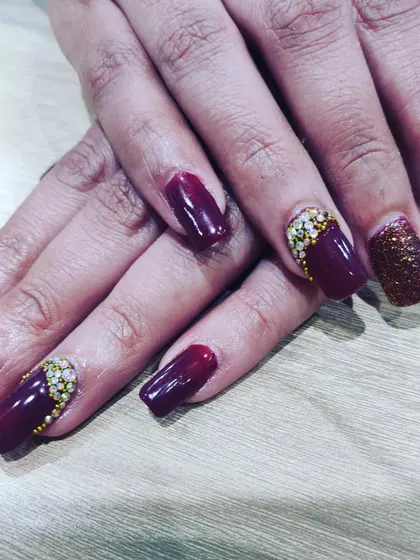 A deep wine-colored nail set with glitter and stone accents. This is a rich and glamorous option for a winter wedding or a cocktail party.