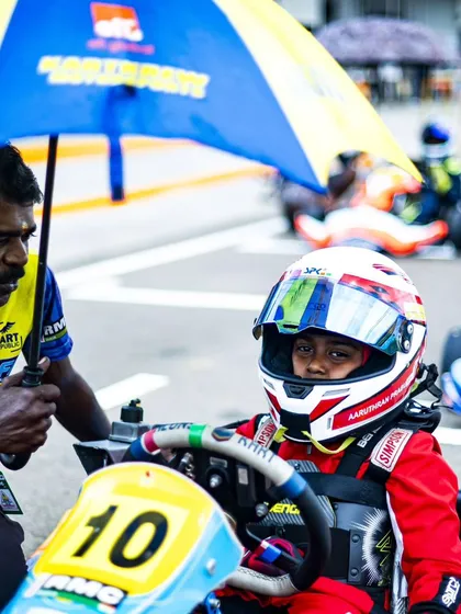A mechanic holds an umbrella for a young driver on the grid, showing our attention to every detail.