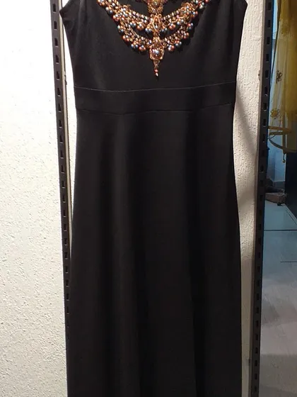 A classic black sheath dress elevated by an ornate, jewel-encrusted neckline. This is a perfect cocktail dress that combines simplicity with a touch of opulence.