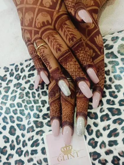 We specialize in creating stunning bridal and festive nail looks. Here, we've paired long, coffin-shaped extensions in a soft pink with silver glitter accent nails, designed to beautifully complement the client's intricate henna design for a wedding celebration.