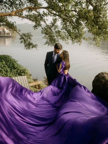 The deep purple trail of this gown fills the frame, creating a luxurious and dramatic effect against the natural lakeside scenery.