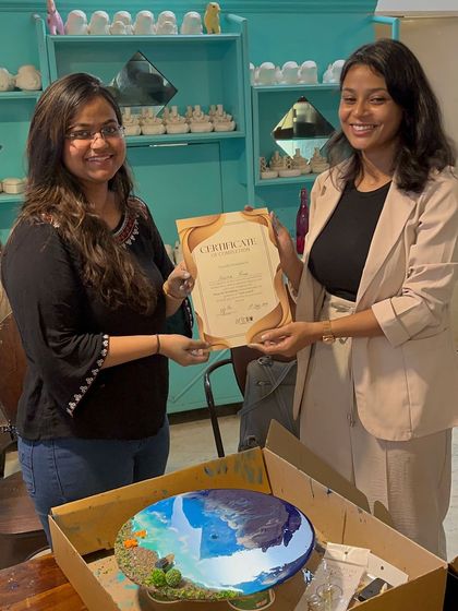 An amazing beach-themed resin art piece created in our workshop. The artist holds her certificate, proud of the realistic ocean waves she crafted.