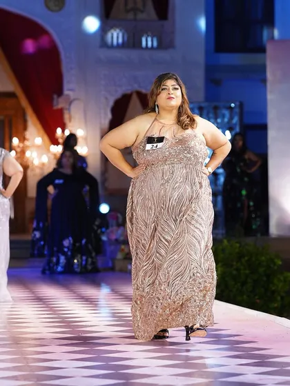 A plus-size model looking radiant in a rose gold sequined gown. The color is flattering on all skin tones and perfect for an evening event.