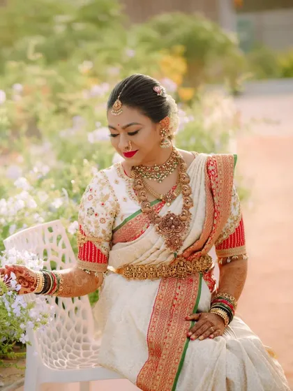 A beautiful portrait of the bride. Her custom puff-sleeve blouse with red accents perfectly matches the border of her traditional white silk saree.