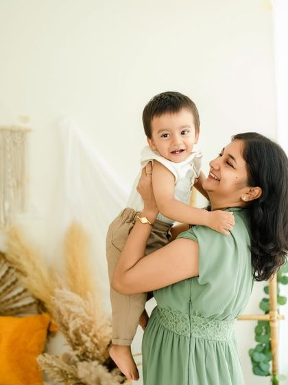 A mother's love. Lifting her son up, their shared smile is a testament to their beautiful bond, captured in our cozy boho studio.