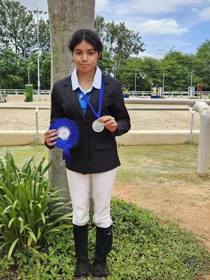 A young rider proudly holds her silver medal and blue ribbon. We celebrate every victory, as it marks a significant milestone in a rider's journey.