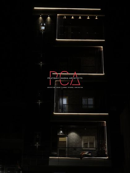 A minimalist night shot focusing on the upper levels of 'The Cursive Abode'. This image emphasizes the clean, glowing lines that define the building's silhouette against the dark sky.