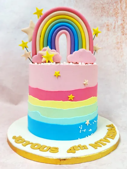 Our Pink Rainbow Cake features a beautiful pastel rainbow topper, fluffy clouds, and a colorful ombre effect on the cake itself.